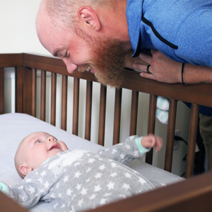 Father looking at baby in crib